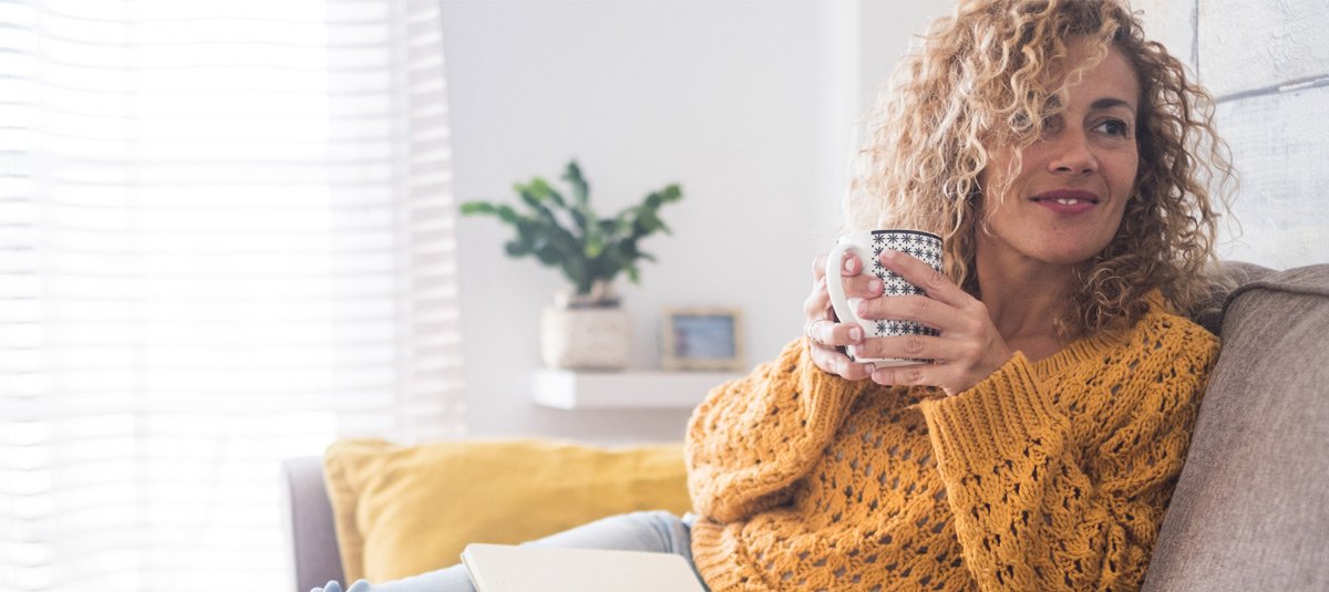 Lady sit down on the sofa drinking tea